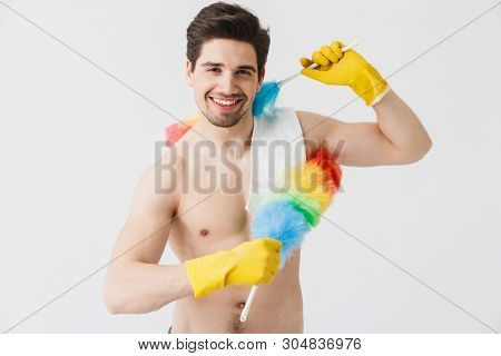 Handsome brunette houseman shirtless standing isolated over white background, using dust cleaner
