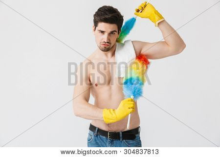 Handsome brunette houseman shirtless standing isolated over white background, using dust cleaner