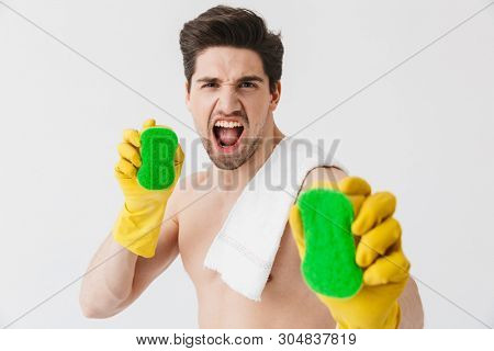 Handsome shirtless brunette houseman standing isolated over white background, holding sponges