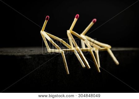 Image Of Three Men With Matchsticks Sitting In The Dark, One Of Them Sad And Erased. Concept Of Lone