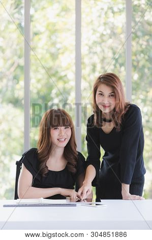 Portrait Of Two Beautiful Asian Successful Businesswomen In Black Dresses Busily Working In Modern O