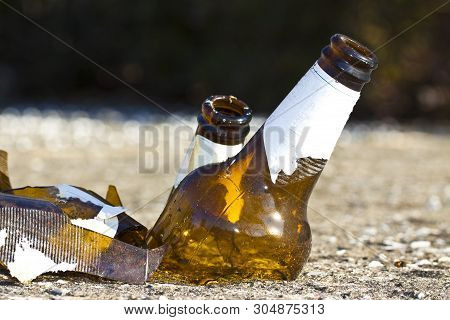 Shattered Beer Bottle Resting On The Ground: Alcoholism Concept