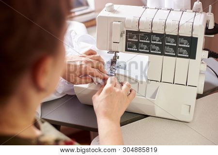 Woman Dressmaker Works By Hands On Overlock With White Thread, Direct Fabric Clamped In Presser Foot