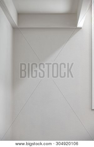 Features of a white room. A sides of a white wooden shelf in light and shadow.