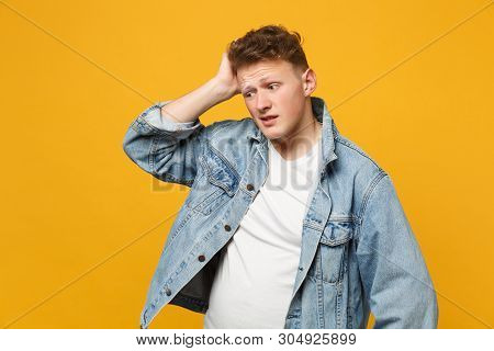 Portrait Of Preoccupied Young Man In Denim Casual Clothes Looking Aside, Putting Hand On Head Isolat