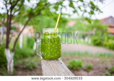  a jar with green cold-pressed juice, nature background. Healthy eating, detoxing, juicing, body cleancing concept 