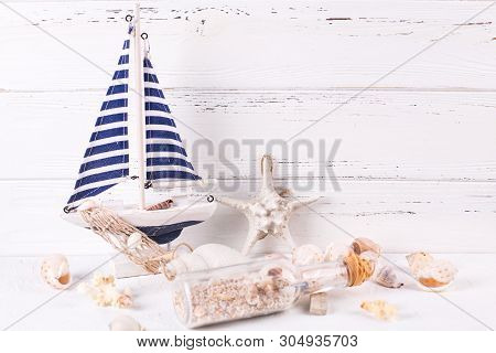 Sea Theme Decorations Near By  Wooden White Wall. Decorative Boat Or Ship, Star Fish, Shell, Bottle 