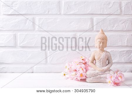 Decorative Buddha And Pink  Cherry Flowers Near By White Brick Wall. Spa Or Still Life Concept. Sele