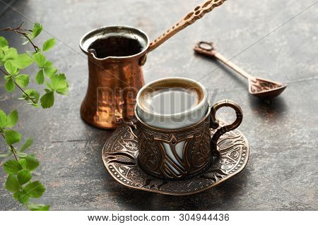 Oriental Coffee Cooked In Traditional Turkish Copper Coffee Pot Poured In A Cup On A Dark Table