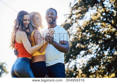 Three friends having fun dancing kizomba on a meadow in afternoon