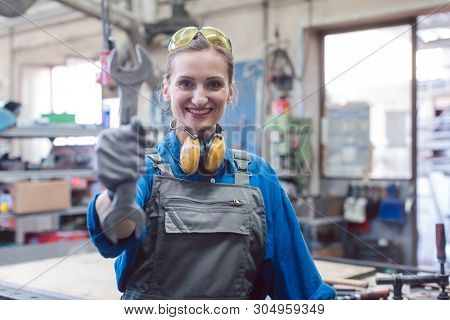 Woman mechanic showing tools to the camera holding wrench in her hand