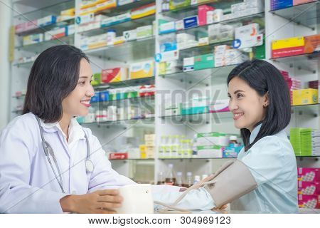 Nurse Taking Hospice Patient Blood Pressure At Drug Store