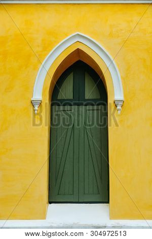 An Arched Green Wooden Door Decorate With White Stucco Arch On The Top In The Yellow Fresco Plaster 