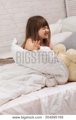 Cute Little Child Girl Wakes Up From Sleep In Bed. Child Shows Gesture Stop. I Do Not Want To Get Up