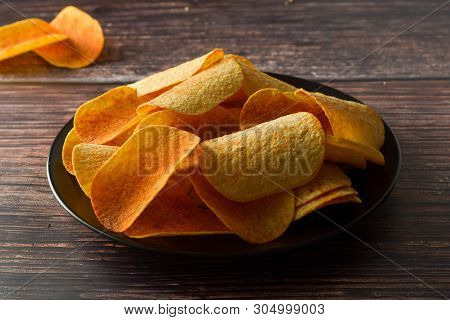 Potato Chips Over Wooden Background. Salty Crispy Snack. Isolated Chips.