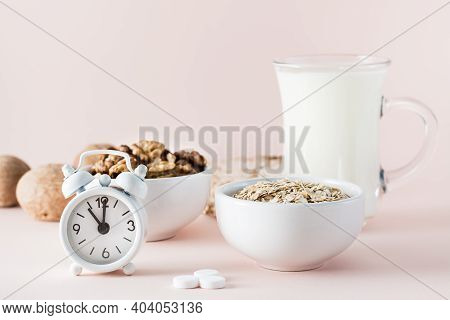 Good Sleep. Foods For Good Sleep - Milk, Walnuts,  Oatmeal, Sleping Pill And Alarm Clock On Pink Bac