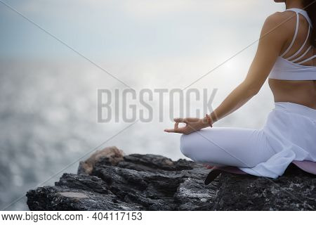 Asian Young Woman Practicing Yoga In Sukhasana Exercise While Looking Out To The Sea.