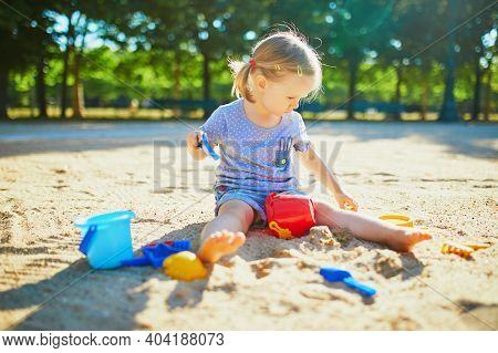 Adorable Little Girl Having Fun On Playground In Sandpit. Toddler Playing With Sand Molds And Making