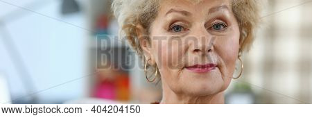 Portrait Of A Beautiful Elderly Woman. Grandmother Is Sitting On The Sofa At Home. Kind Look Of An E