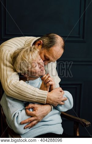 Portrait Of Old Couple Wife And Husband Hugging And Smiling. Dark Blue Background. Happy Lovers On R