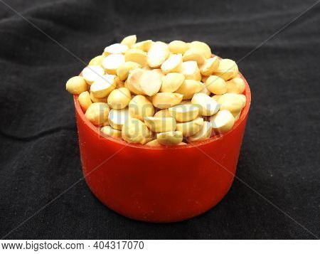 Roasted Gram Pile In A Red Color Plastic Cup And Traditional Sand Bowl With Scattered On Black Backg