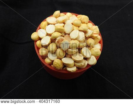 Roasted Gram Pile In A Red Color Plastic Cup And Traditional Sand Bowl With Scattered On Black Backg
