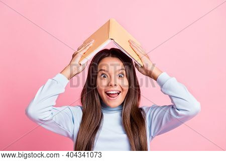 Close-up Portrait Of Lovely Overjoyed Cheerful Girl Holding Book Over Head Having Fun Isolated Over 