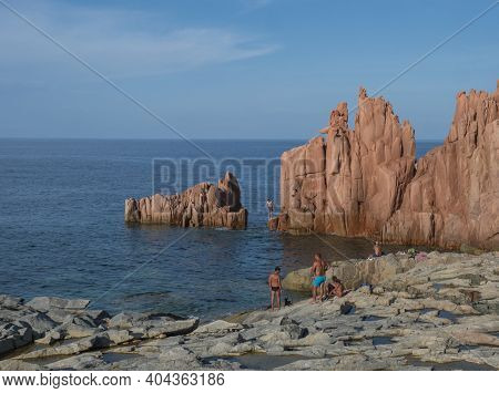 Arbatax, Sardinia, Italy, September 9, 2020: Two Young Men Jumping From Red Rocks, Rocce Rosse At Me