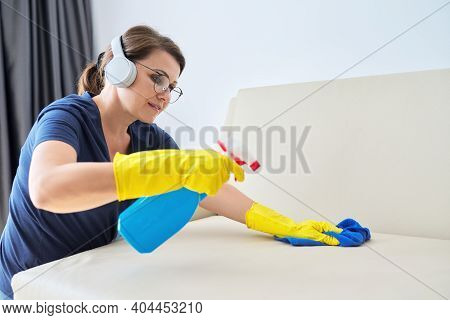 Woman Doing House Cleaning, Female In Headphones And Gloves With Detergent Washing Furniture In Room