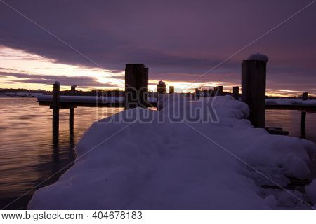Wooden Snow Covered Pier With A Stunning Sunset In The Background