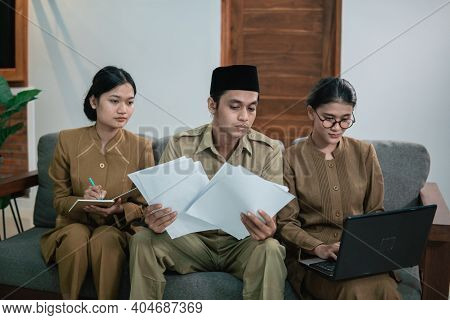 A Serious State Official Holding A Paper And Two Female Assistants In Civil Servant Uniforms