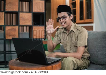 Man In Civilian Uniform Use Laptop While Sitting With Hand Gestures To Say Hello