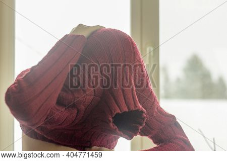 The Young Man Pulls A Warm Red Sweater Over His Head.