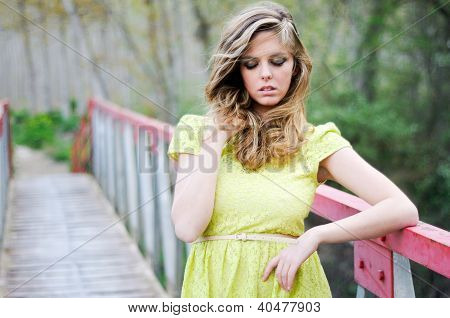 schÃ¶nes blondes MÃ¤dchen, gekleidet mit einem Beige Kleid, mit geschlossenen Augen in einer lÃ¤ndlichen BrÃ¼cke, stehend