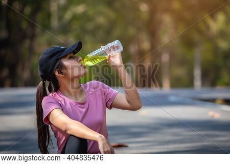 Close-up Of Beautiful Asian Woman Sport Athletes Drinking Water With Electrolytes After Exercise. As