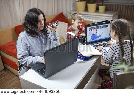 Kids Doing Homework And Mother Working Online In One Room, Distant Education At Home