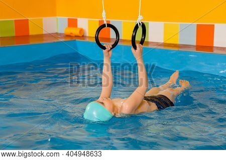 Child In Swimming Pool Excersizing With Sport Rings
