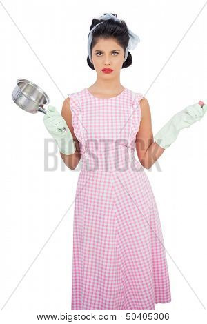 Disppointed black hair model holding a pan and wearing rubber gloves on white background 