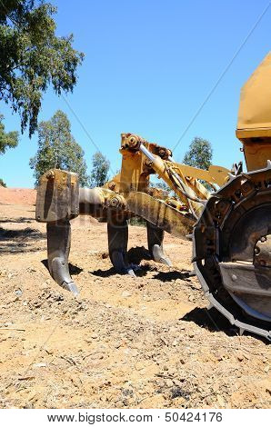 Ripper tool on yellow bulldozer.