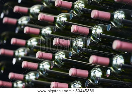 Bottles of wine in row stacked in cellar. shallow depth of view.