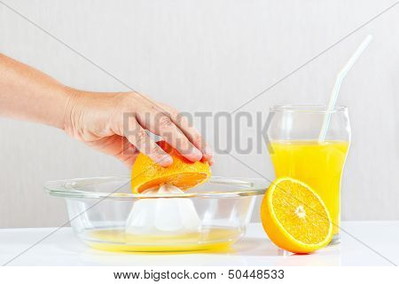 Woman's hand making fresh juice from oranges with a juicer
