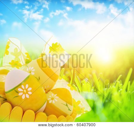 Easter eggs in the basket on fresh grass meadow, bright sun shine, eggs painted with yellow colours and floral ornament, traditional religious symbol for Eastertime 