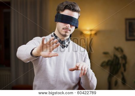 Blindfolded Young Man At Home In Living Room Cannot See