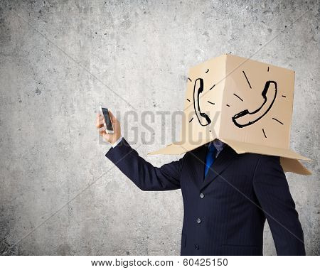 Businessman using mobile phone wearing carton box on head