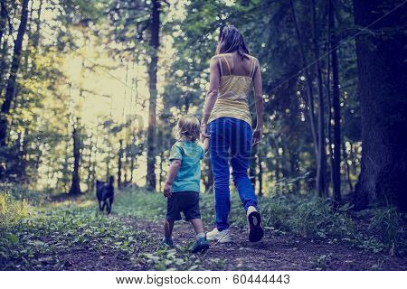 Woman And Child Walking A Dog In The Forest