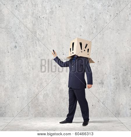 Businessman using mobile phone wearing carton box on head