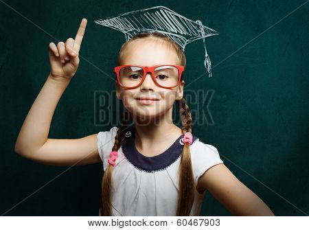 Genius girl in red glasses near blackboard in master hat