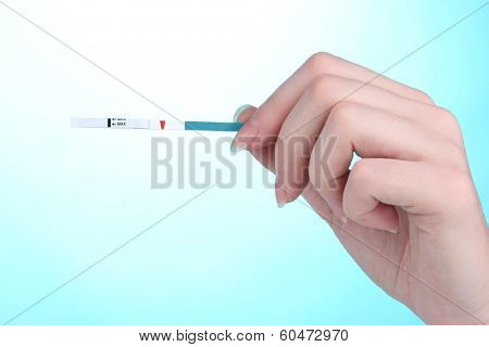 pregnancy test in hand on blue background