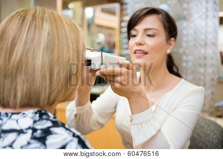 Female optometrist measuring pupilary distance on senior patient