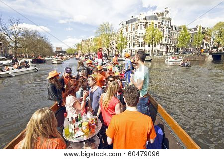 AMSTERDAM, HOLLAND - APRIL 30, 2013: Amsterdam canals full of boats and people in orange during the celebration of queensday 